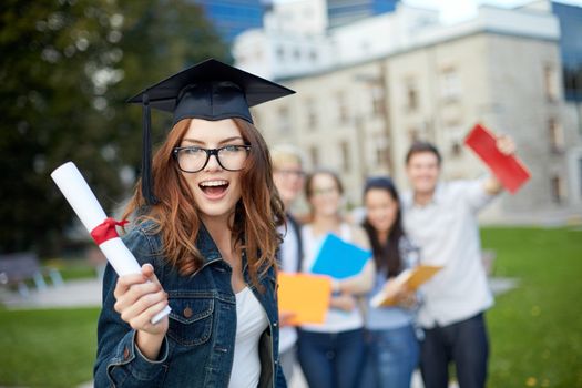 education, graduation and people concept - group of smiling students in mortarboard with diploma and school folders