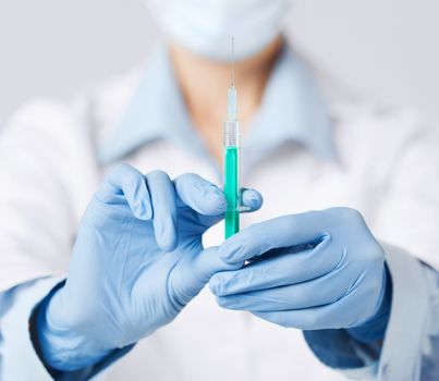 healthcare and medical concept - close up of female doctor holding syringe with injection