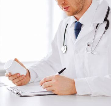 healthcare, hospital and medical concept - male doctor writing prescription paper and capsules