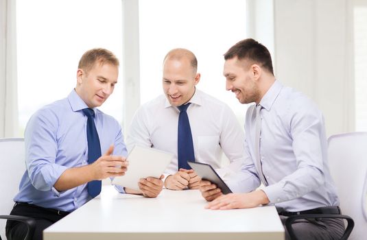 business, technology and office concept - three smiling businessmen with tablet pc computers in office