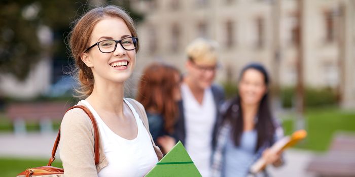 education, campus, friendship and people concept - group of happy teenage students with school folders