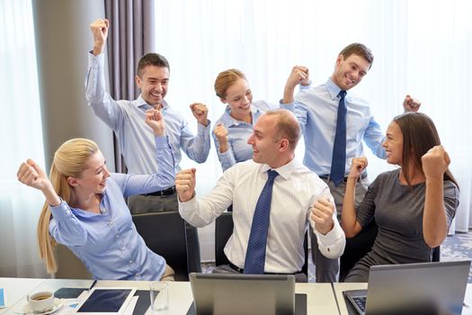 business, people, technology, gesture and teamwork concept - smiling business team raising hands and celebrating victory in office