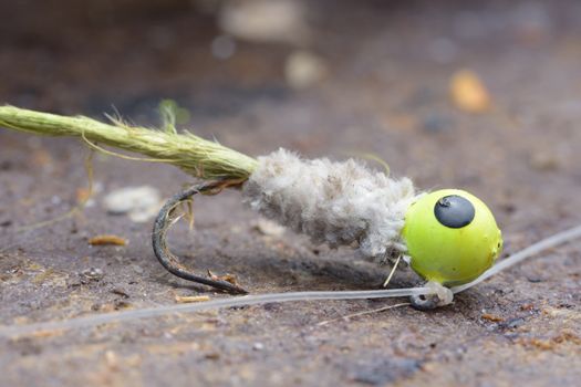 Macro closeup of rusty old fishing jighead lure with textured body and feather tied to monofilament line