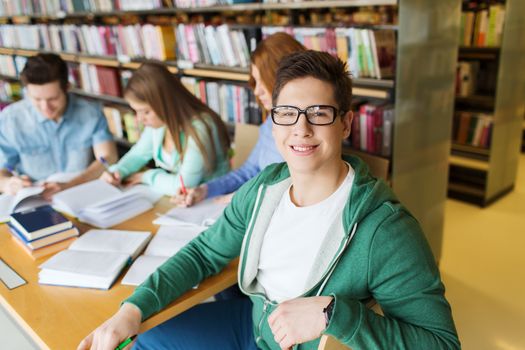 people, knowledge, education and school concept - happy student boy reading books in library