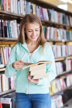 people, knowledge, education and school concept - happy student girl or young woman with book in library