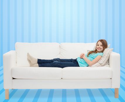 home, leisure, people and happiness concept - smiling little girl lying on sofa over blue striped background