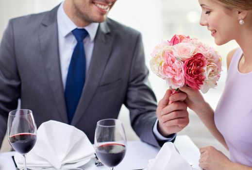 restaurant, people, celebration and holiday concept - smiling young couple with glasses of red wine looking at each other at restaurant