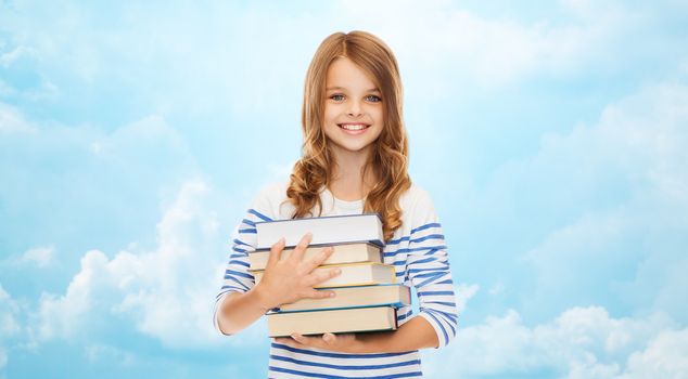 education, people, children and school concept - happy little student girl with many books over blue sky with clouds background