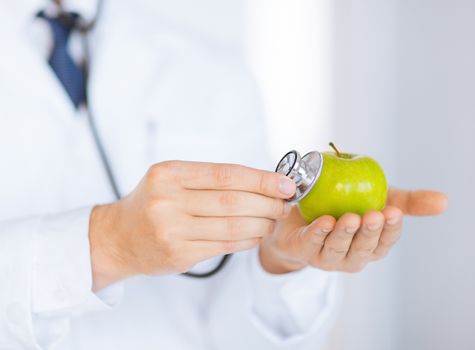 close up of male doctor with green apple and stethoscope