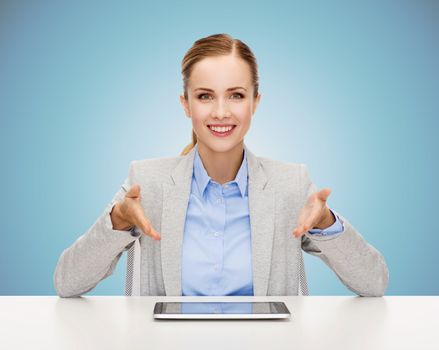 business, technology, education and people concept - smiling businesswoman sitting at table with tablet pc computer over blue background