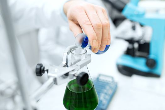 science, chemistry, biology, medicine and people concept - close up of scientist hand filling test tubes and making research in clinical laboratory