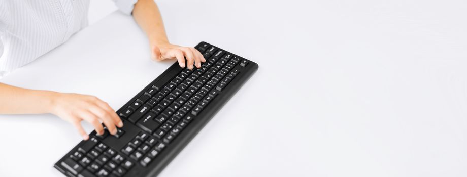 education, school and technology concept - little student girl hands typing on keyboard with copyspace