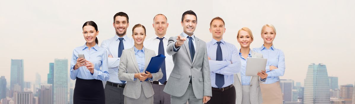 business, people, corporate, teamwork and office concept - group of happy businesspeople pointing at you over city background
