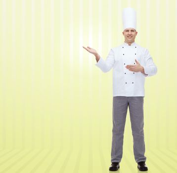 cooking, profession and people concept - happy male chef cook inviting over yellow background