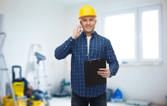 repair, building, construction and maintenance concept - smiling man or builder in helmet with clipboard calling on smartphone over storeroom background