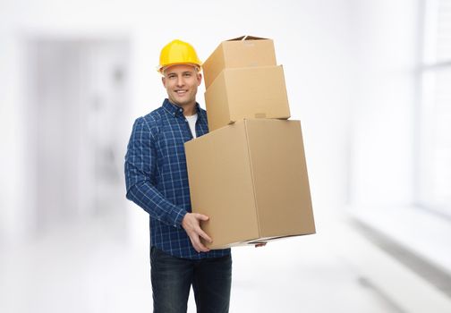 repair, building, construction, loading and delivery concept - smiling man or loader in helmet with cardboard boxes over room background
