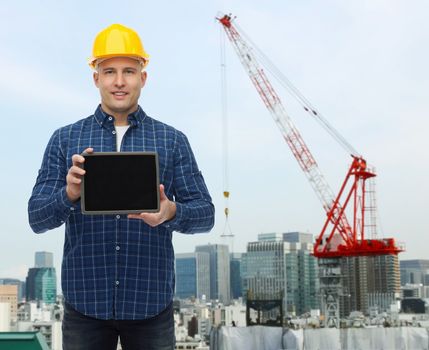 repair, building, people and maintenance concept - smiling male builder or manual worker in helmet showing tablet pc computer blank screen over city construction site background