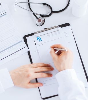 close up of male doctor writing prescription paper