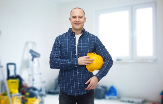 repair, building, construction and maintenance concept - smiling man holding helmet over storeroom background