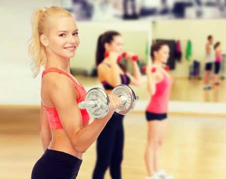 fitness, healthcare and exercise concept - young sporty woman with heavy steel dumbbell