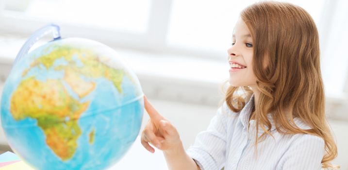 education and school concept - smilng little student girl with globe at school