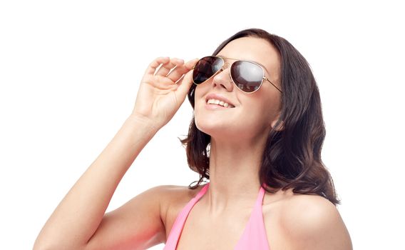 people, fashion, swimwear, summer and beach concept - happy young woman in sunglasses and pink swimsuit looking up