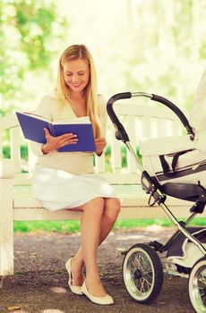 family, child, leisure, education and parenthood concept - happy mother with baby stroller reading book in park