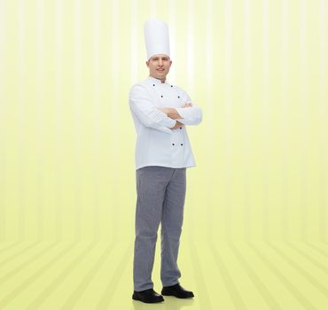 cooking, profession and people concept - happy male chef cook with crossed hands over yellow background