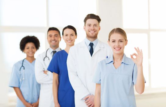 international, profession, people and medicine concept - group of happy doctors and nurses at hospital showing ok hand sign