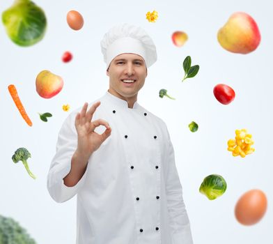 cooking, profession, gesture, vegetarian diet and people concept - happy male chef cook showing ok sign over blue background with falling vegetables