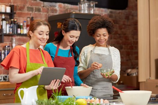 cooking class, friendship, food, technology and people concept - happy women with tablet pc computer in kitchen