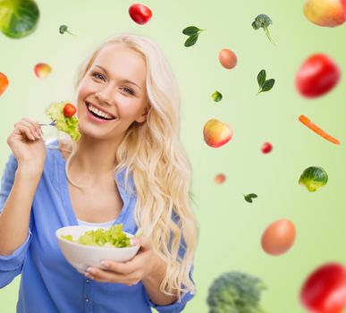 people, healthy eating, dieting and food concept - smiling young woman eating vegetable salad over green background