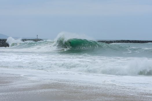 NEWPORT BEACH, USA - MAY 4, 2015: A body surfer falls like a rag doll from inside the crest of a huge wave as it breaks at the famous California surf destination called The Wedge, during a storm fueled high surf at Newport Beach, California.