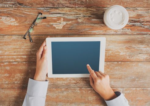 business, education, people, advertisement and technology concept - close up of hands pointing finger to tablet pc computer screen with coffee cup and eyeglasses on table