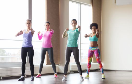 fitness, sport, training, gym and martial arts concept - group of women working out and fighting in gym