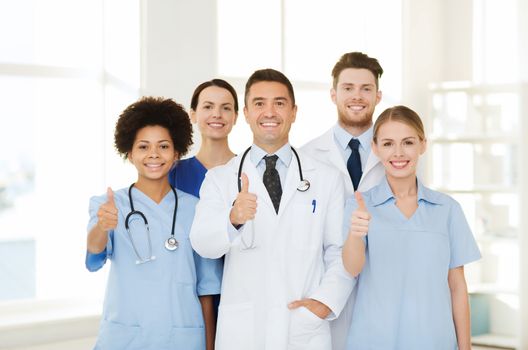 hospital, profession, people and medicine concept - group of happy doctors at hospital showing thumbs up gesture