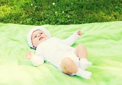 child, childhood and toddler concept - smiling baby lying on blanket and looking up