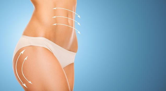 people, health, body care and beauty concept - close up of slim woman tummy and hips in underwear over blue background