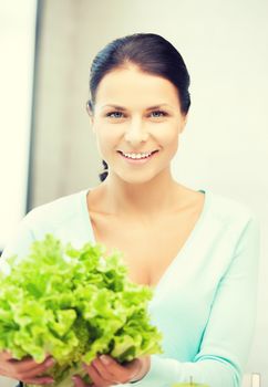 beautiful woman in the kitchen with green salad leaves..