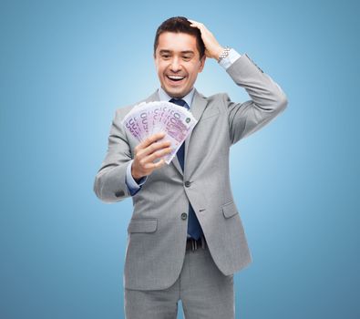 business, people and finances concept - happy laughing businessman with euro money over blue background