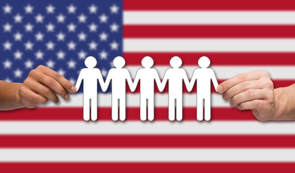 community, unity, international, social equality and teamwork concept - close up of multiracial couple hands holding paper chain people over american flag background