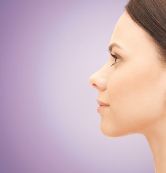 health, people, plastic surgery and beauty concept - beautiful young woman face over violet background