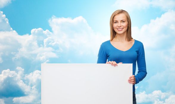 people, advertisement and sale concept - smiling young woman with blank white board over blue sky and clouds background