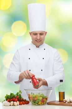 profession, vegetarian, food and people concept - happy male chef cooking and seasoning vegetable salad over green lights background