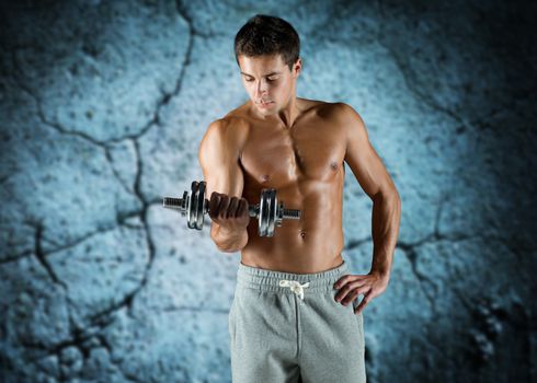 sport, fitness, weightlifting, bodybuilding and people concept - young man with dumbbell flexing biceps over concrete wall background