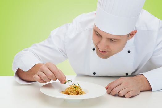 cooking, profession, haute cuisine, food and people concept - happy male chef cook decorating dish over green background