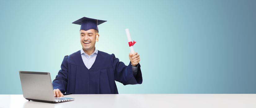 education, graduation, business, technology and people concept - happy adult student in mortarboard with diploma and laptop computer sitting at table over blue background