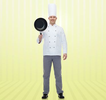 cooking, profession and people concept - happy male chef cook holding frying pan over yellow background