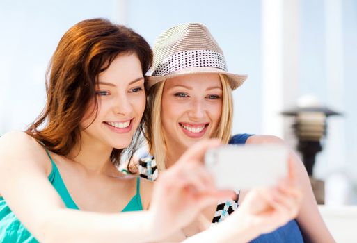 summer holidays and vacation - girls taking photo in cafe on the beach