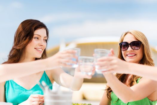 summer holidays and vacation - girls making a toast in cafe on the beach